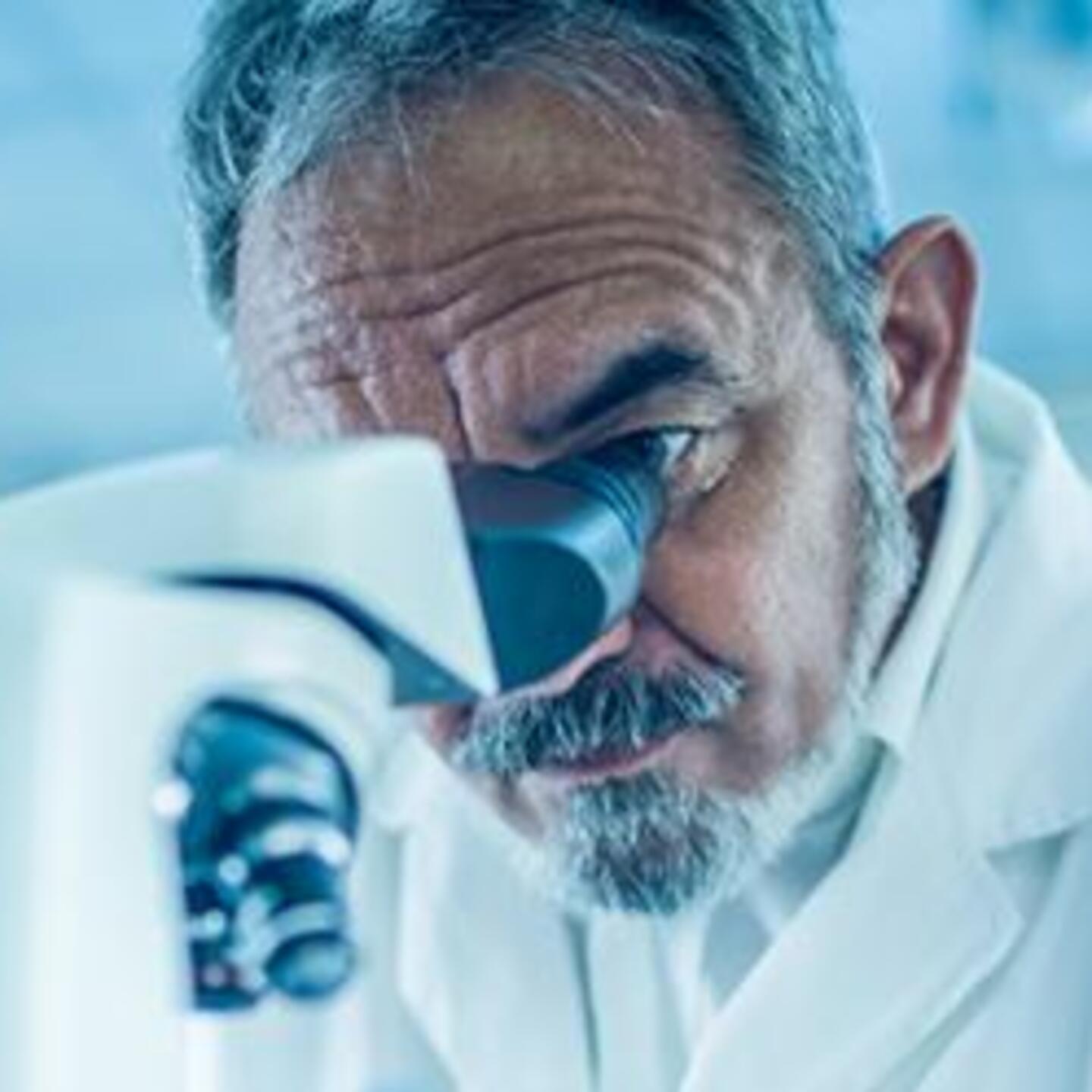 Homme scientifique en blouse blanche dans son laboratoire de recherche et regardant dans un microscope