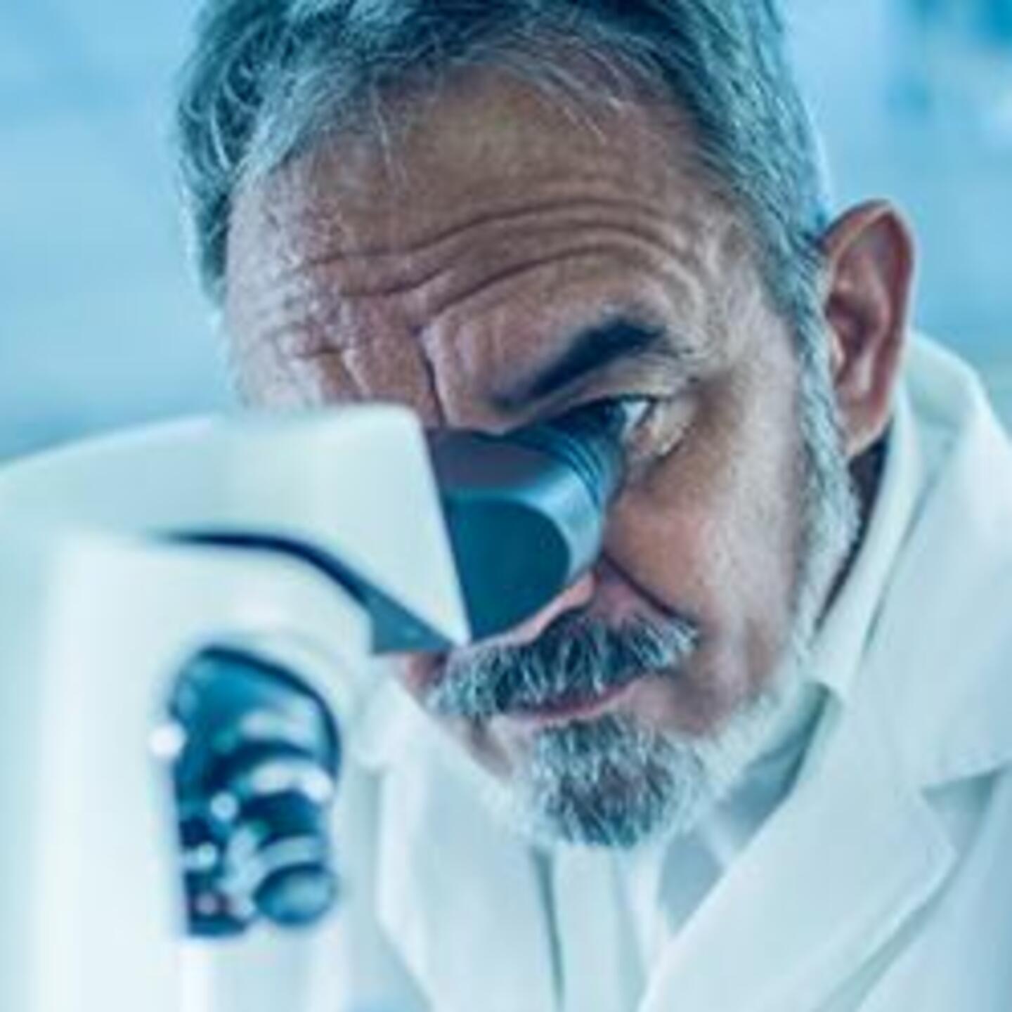 Un scientifique en blouse blanche, regardant dans un microscope, dans un laboratoire de recherche